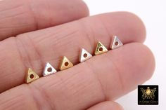 five tiny triangle shaped studs in gold and silver on a person's finger