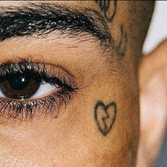 a close up of a person with tattoos on his face and eyeliners, looking at the camera