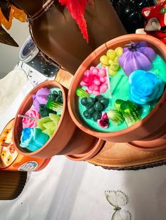 three clay pots filled with fake flowers on top of a table