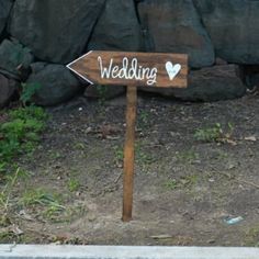 a wooden sign with the word wedding written on it in front of a rock wall