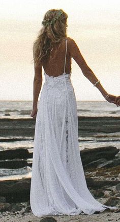 a woman standing on top of a beach holding hands