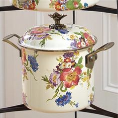 two pots with floral designs on them are sitting on a rack in front of a door