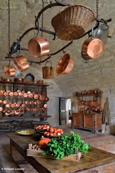 an old fashioned kitchen with copper pots and pans hanging from the ceiling