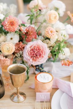 the table is set with pink and white flowers in vases, silverware, and napkins