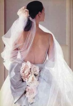 the back of a bride's wedding dress with flowers on her hair and veil