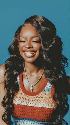 a woman smiling and wearing a multicolored tank top with her hair in curls