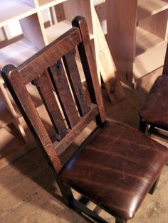 two wooden chairs sitting next to each other in a room with shelves and flooring