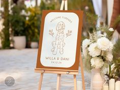 a wooden easel with a sign that says welcome to the couple and their dog