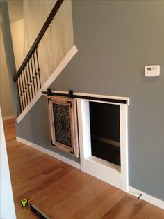 a dog house built into the side of a stair case in a room with hard wood flooring