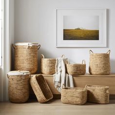 several woven baskets are stacked on top of each other in front of a framed photograph