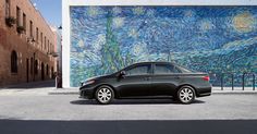 a black car parked in front of a wall with a painting on it's side