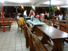 a group of people sitting at wooden tables in a room with white tile flooring