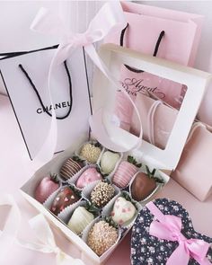 a box filled with assorted chocolates next to a pink bag and white ribbon