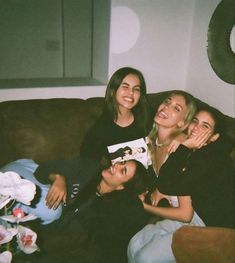 three people sitting on a couch with one woman smiling and the other looking at the camera