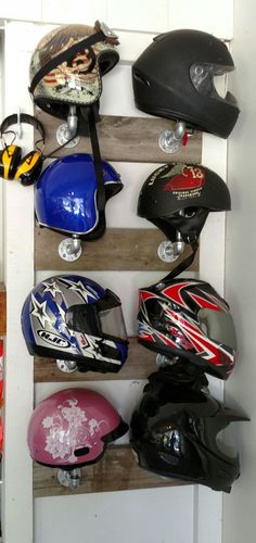 several helmets are lined up on wooden shelves