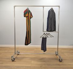 a clothes rack with two shirts hanging on it's sides and one folded shirt