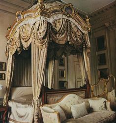 an ornate canopy bed in a bedroom with white walls