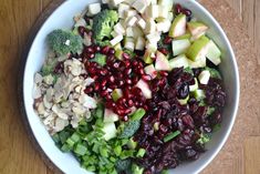 a bowl filled with broccoli, apples, cranberries and other vegetables