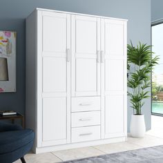 a white armoire in a blue living room next to a large window and potted plant