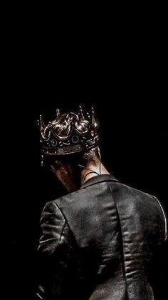 a man in a suit with a crown on his head looking down at the ground