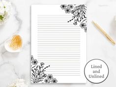 lined paper with black and white flowers on it next to a cup of pencils