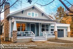 a small gray and white house with stone pillars on the front porch, covered in fall leaves