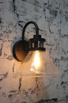 a light that is on the side of a wall with a brick wall behind it