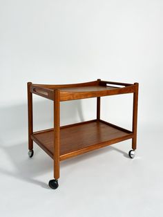 a small wooden table with wheels on the bottom and one shelf below it, against a white background