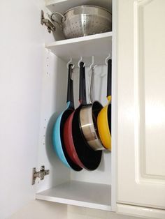 an open cabinet with pots and pans hanging from it