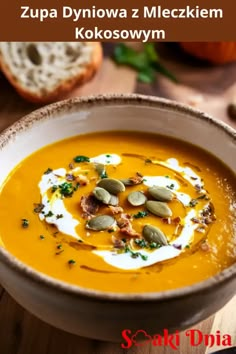 a white bowl filled with carrot soup and topped with sour cream, pumpkin seeds and capers