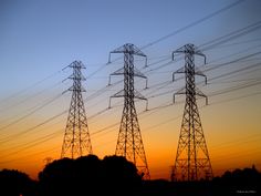 the sun is setting behind power lines and telephone poles in an area with many electrical towers