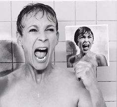 a shirtless woman holding up a photo of a man in the shower with his mouth open