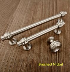 two metal handles on top of a wooden table with the words, brushed nickel