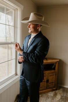 a man in a cowboy hat standing next to a window