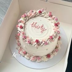 a white cake with pink flowers and the word thirty on it in a box that is open