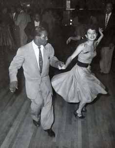 an old photo of two people dancing on the dance floor