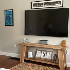 a flat screen tv mounted on the wall above a wooden table in a living room