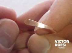 a hand holding a gold ring with the word victory does written in white lettering on it