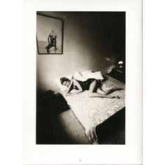 a woman laying on top of a bed next to a framed picture above her head