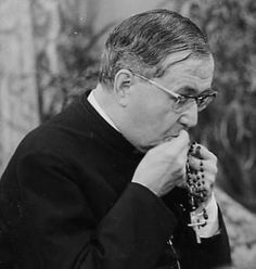 an old photo of a man in glasses and a suit eating something out of his mouth