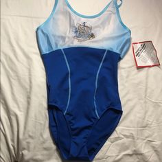 a women's blue and white swimsuit laying on top of a bed next to a tag