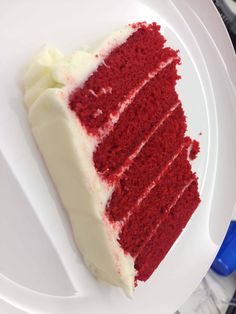 a slice of red velvet cake with white frosting sits on a plate, ready to be eaten