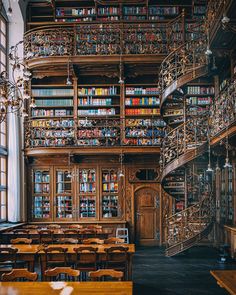 an old library with many bookshelves and tables in front of the stairs,