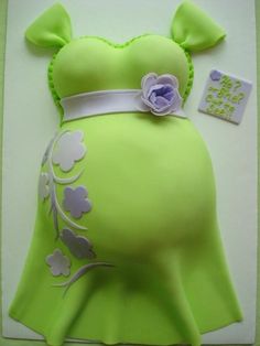 a pregnant woman's green dress cake with white flowers on the side and purple ribbon around the waist