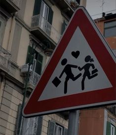 a red and white street sign on a pole in front of a building with balconies