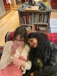 two women sitting on a couch looking at something