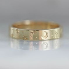 Why I Love It: A band that is perfect for any time of day or night in this wider version of our best selling engraved bands. Swift and careful hand movements create this motif of crescent moons, stars, planets and sun rays. Engraved texture with precise detail and extraordinary design in your choice of golds. All hand engraved locally in San Francisco, CA. The Details: 14k Yellow Gold, 14k White Gold, 14k Rose Gold, 18k Peach Gold Band Width is Approx. 3.50 mm Made to order in your size, please Engraved Gold Band, Adjustable Celestial Engraved Jewelry, Celestial 14k Gold Round Band Jewelry, Celestial Style 14k Gold Round Band Jewelry, Gold Moon-shaped Promise Jewelry, Gold Moon Shaped Promise Jewelry, Gold Moon-shaped Jewelry For Promise, Gold Celestial Engraved Ring As Gift, Gold Celestial Engraved Rings