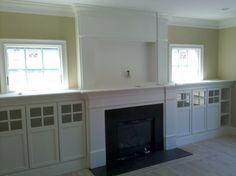 an empty living room with a fireplace and built in cabinets