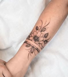 a woman's arm with a flower tattoo on her left arm and the wristband