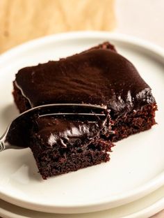 a piece of chocolate cake on a white plate with a fork in it and a bite taken out